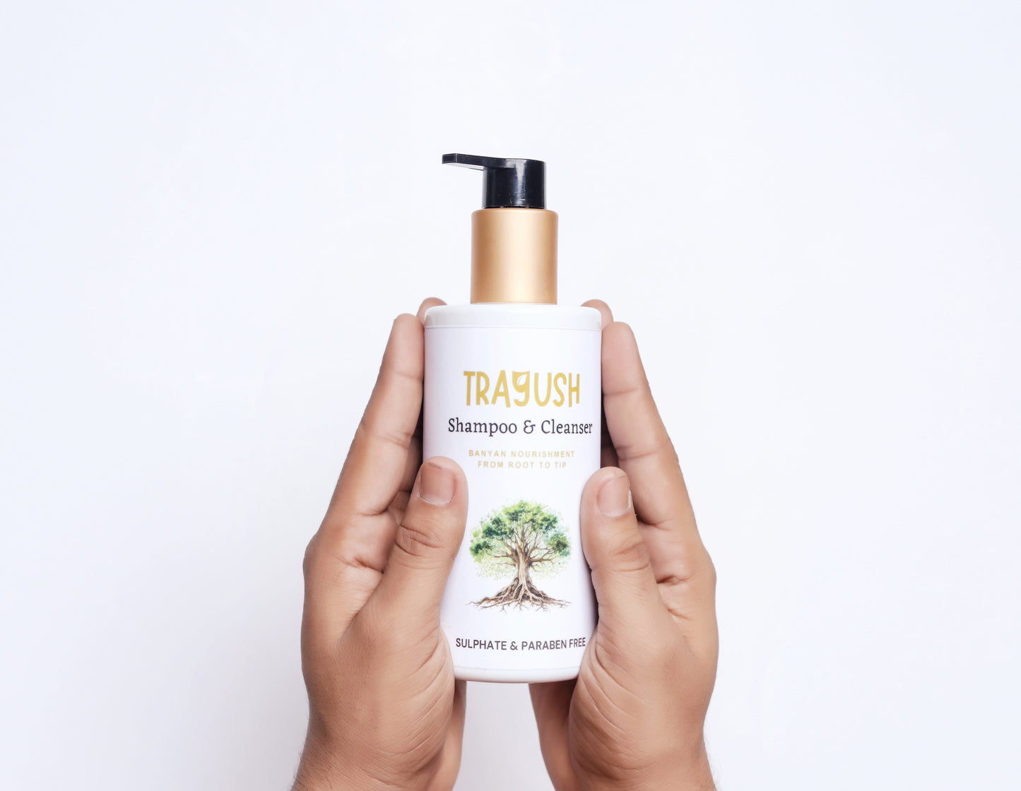 Hand holding a TRAYUSH shampoo & cleanser bottle on a white background