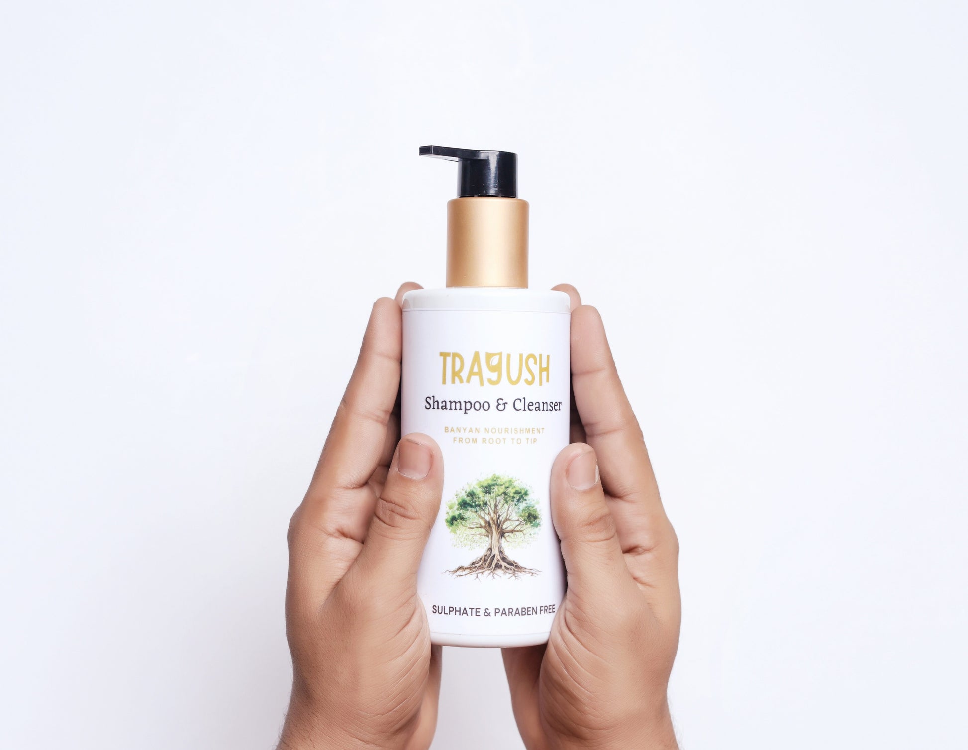 Hand holding a TRAYUSH shampoo & cleanser bottle on a white background
